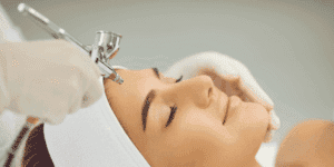 Donna durante un trattamento di ossigenoterapia viso in istituto estetico, con applicazione di ossigeno tramite aerografo professionale.