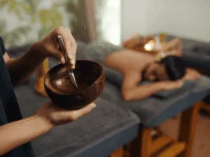 Estetista applica un trattamento peeling al corpo su una cliente sdraiata, concentrandosi sulla schiena.