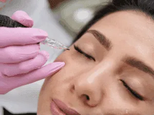Professionista del trucco semipermanente che applica eyeliner sfumato sulla palpebra superiore.