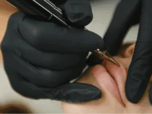 Dermopigmentista esegue il trucco semipermanente labbra con dermografo professionale, indossando guanti neri