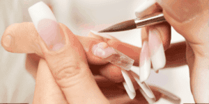 Applicazione del gel acrilico durante la ricostruzione unghie professionale in salone estetico.